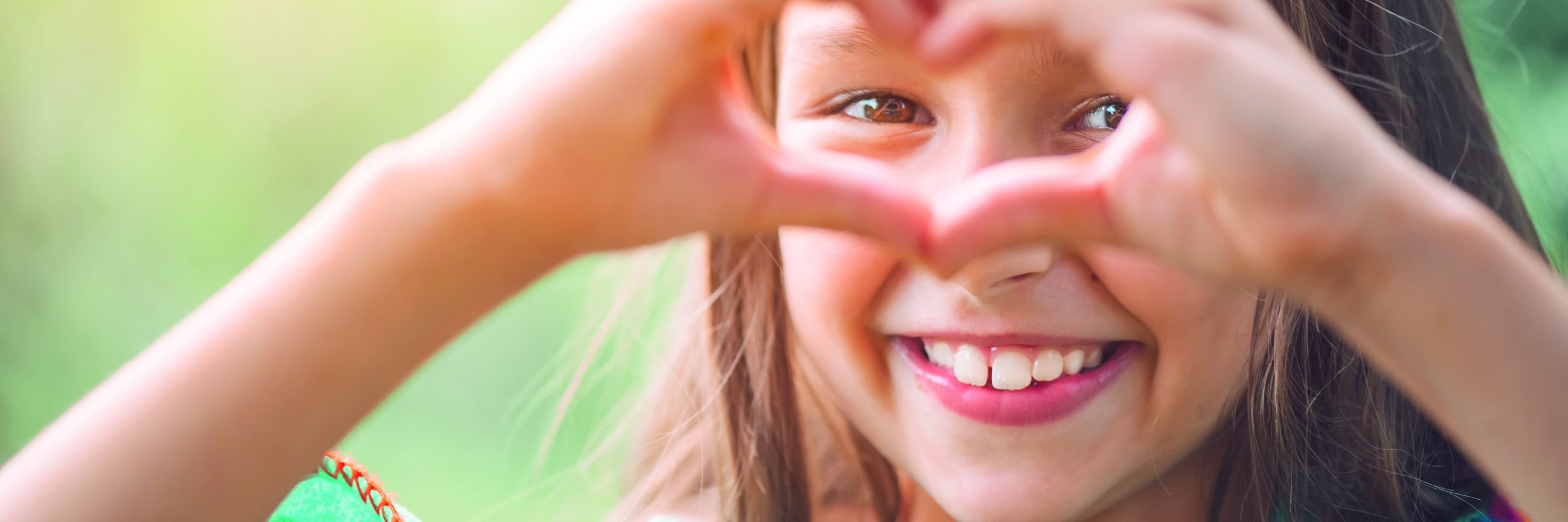 Lachendes Kind Ein lachendes Mädchen, was ihre Hände zu einem Herz formt