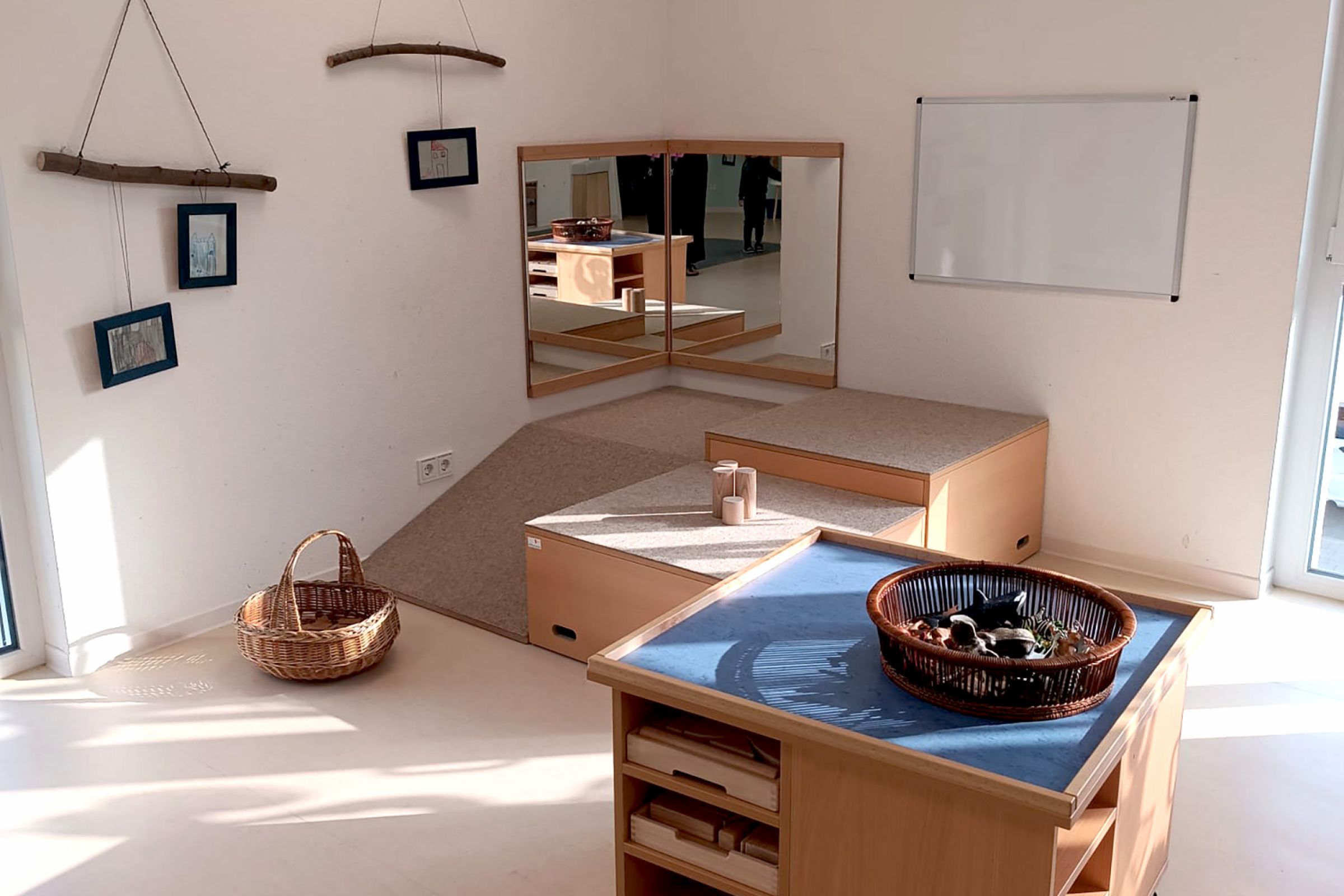 Kita Orwischer Entdecker - Gruppe 2 Eine Spielecke in der Kita mit Spiegel, Whiteboard und Bauklötzen in einer Kommode.