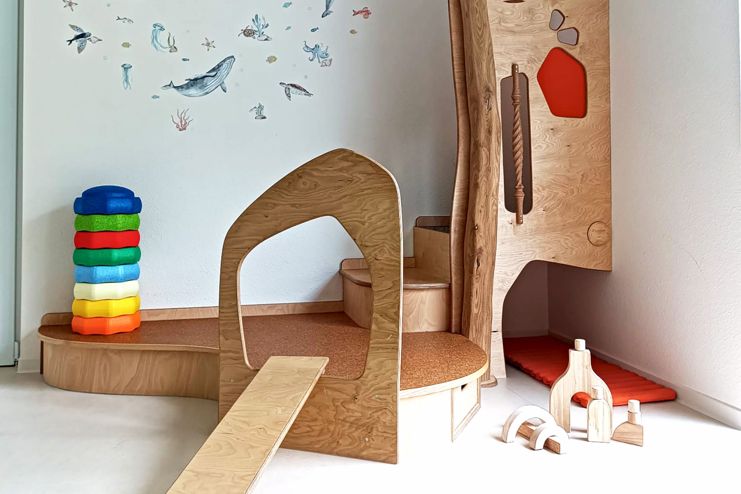 Kita Orwischer Entdecker - Gruppe 3 Eine Spielecke in der Kita mit einem kleinen Klettergerüst und Stapelsteinen, die zum spielen einladen.