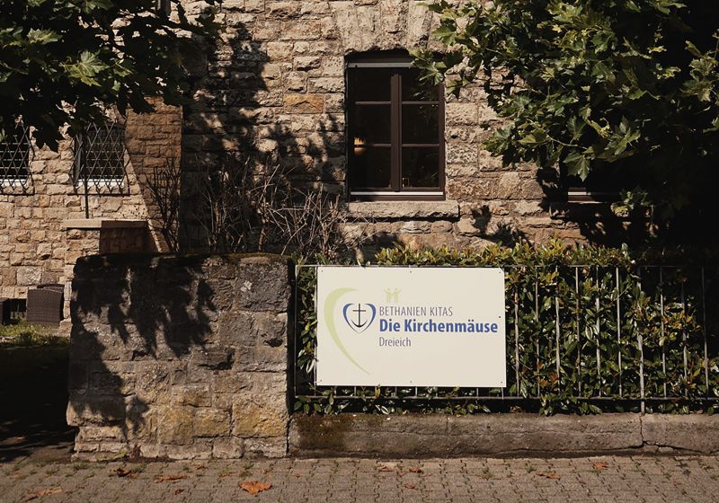 Kita Die Kirchenmäuse - Titelbild Die Hausfront des Kita Gebäudes mit dem Schild des Logos der Kita Die Kirchenmäuse.